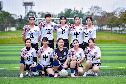 Group of women football players posing on a field in Hanoi, Vietnam, showcasing team spirit.