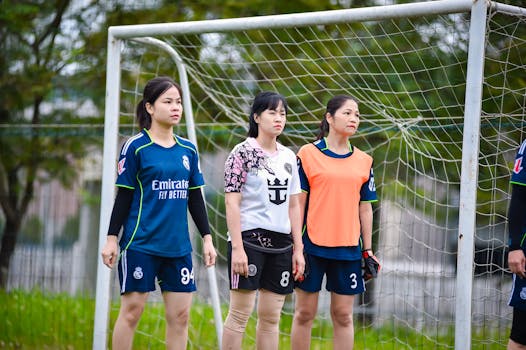 Three female football players stand by the goal post, showcasing team spirit in Hanoi, Vietnam.