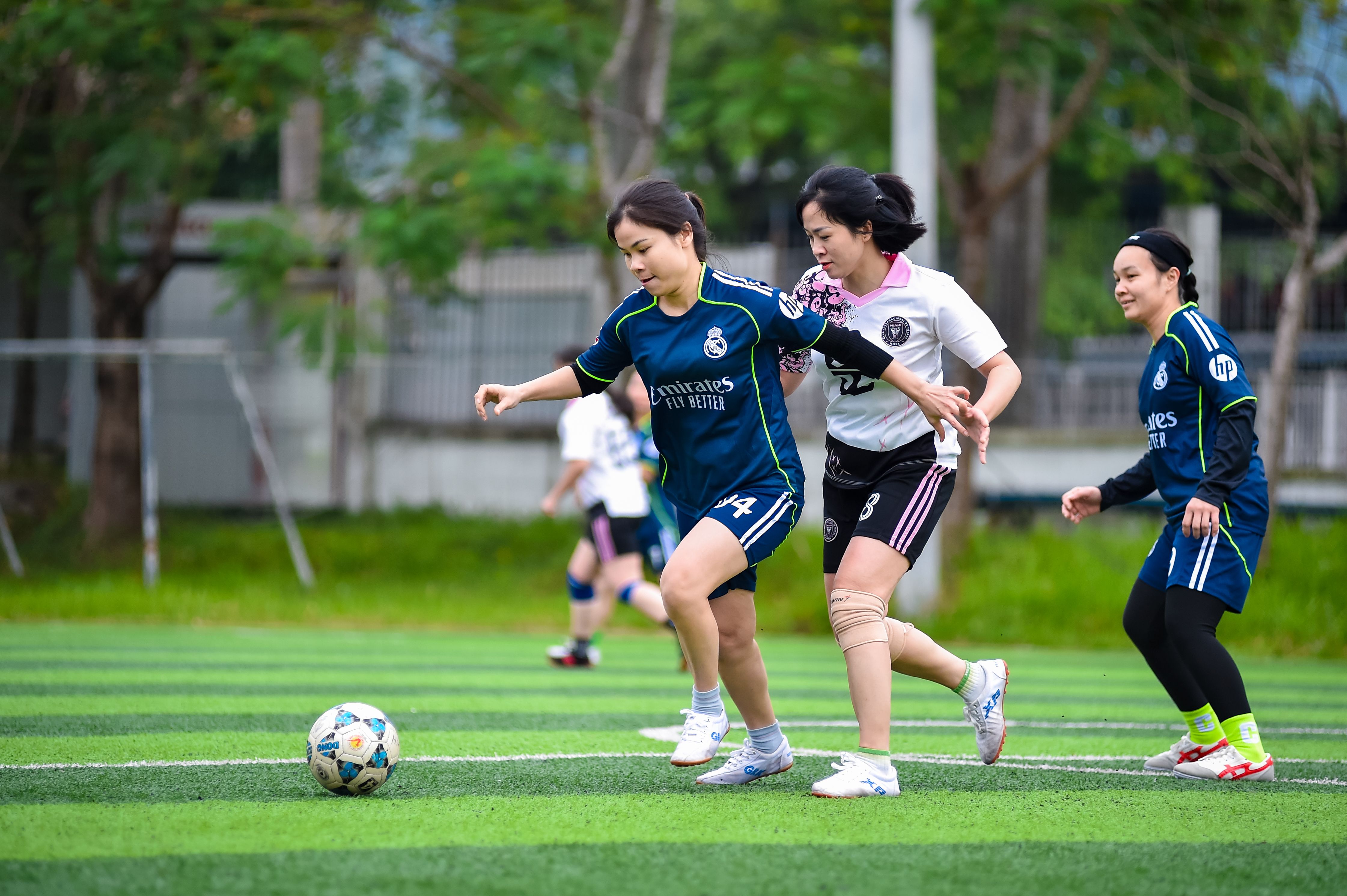 Group of women engaging in a lively football match on a green field in Hanoi, Vietnam.