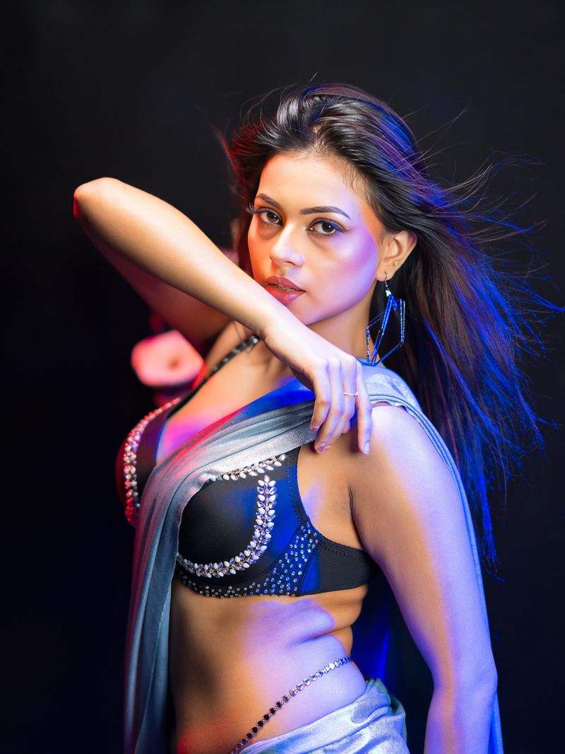 Elegant Indian woman posing in traditional attire with striking lighting.