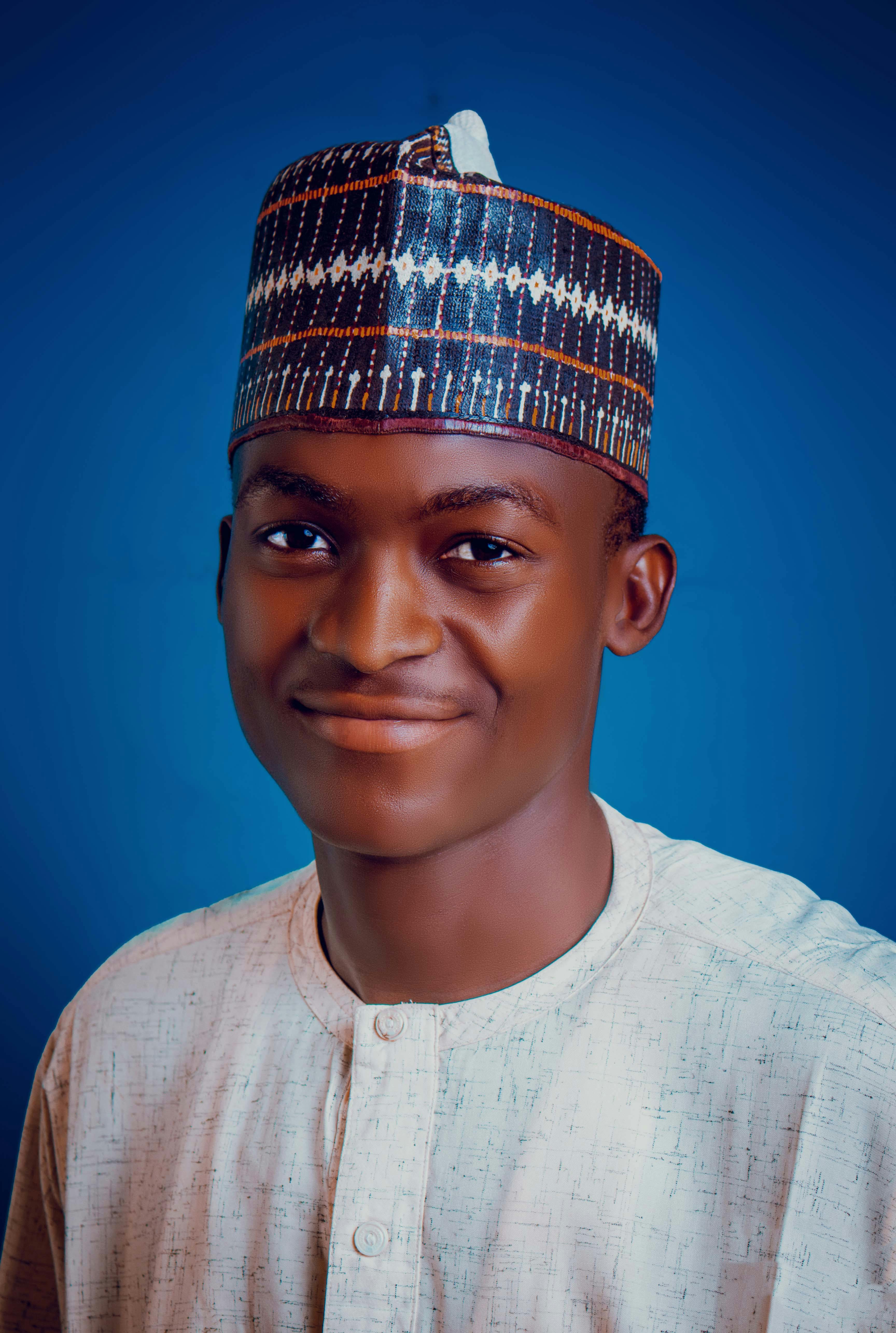 Young man in traditional attire with a blue background, exuding warmth.