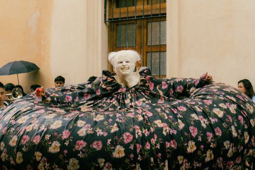A performer in elaborate floral attire entertains during a festive event in San Cristóbal de las Casas, Mexico.