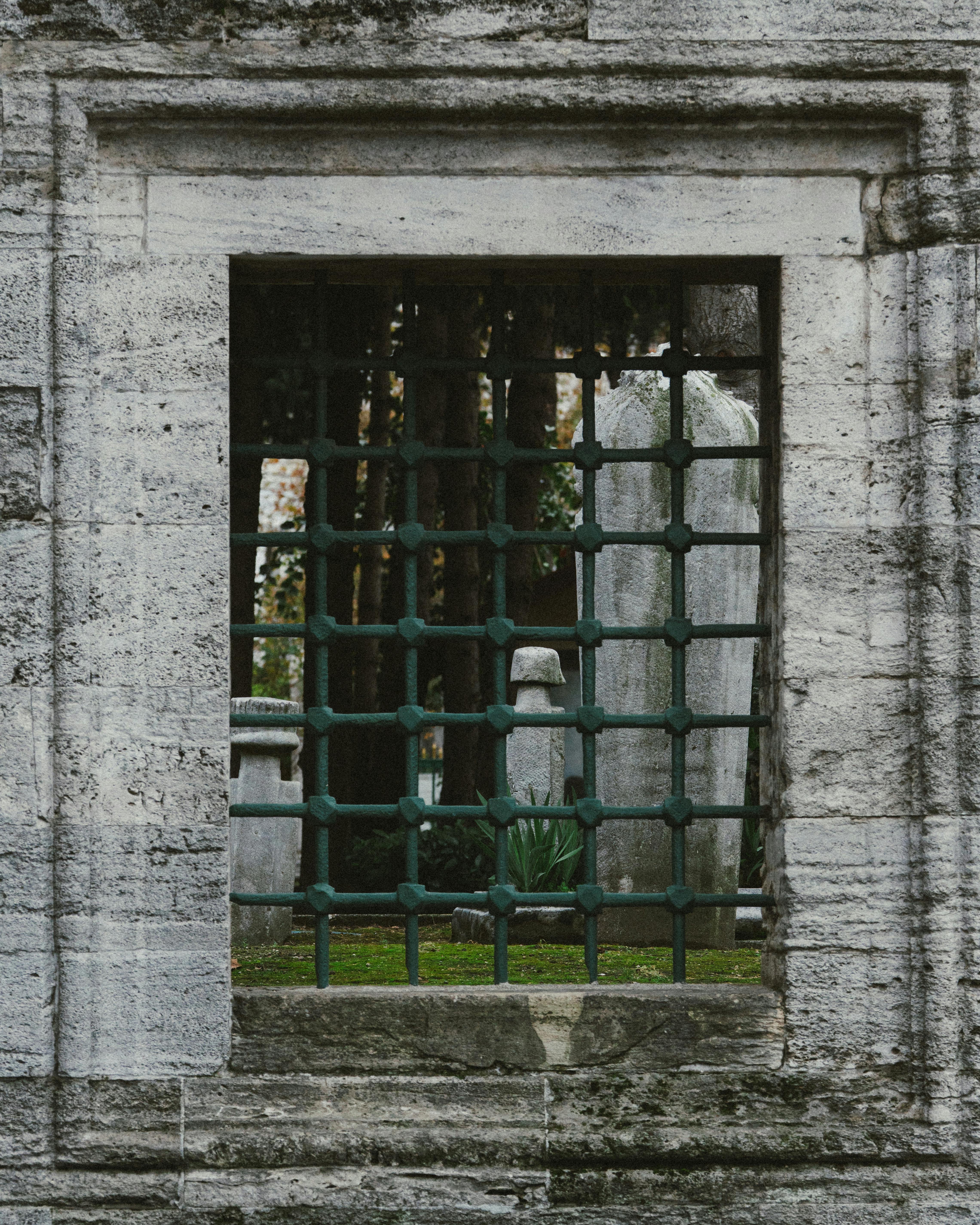 De franc Una làpida es veu a través d'una finestra de pedra amb una reixa de ferro, que captura l'arquitectura històrica. Foto d'estoc