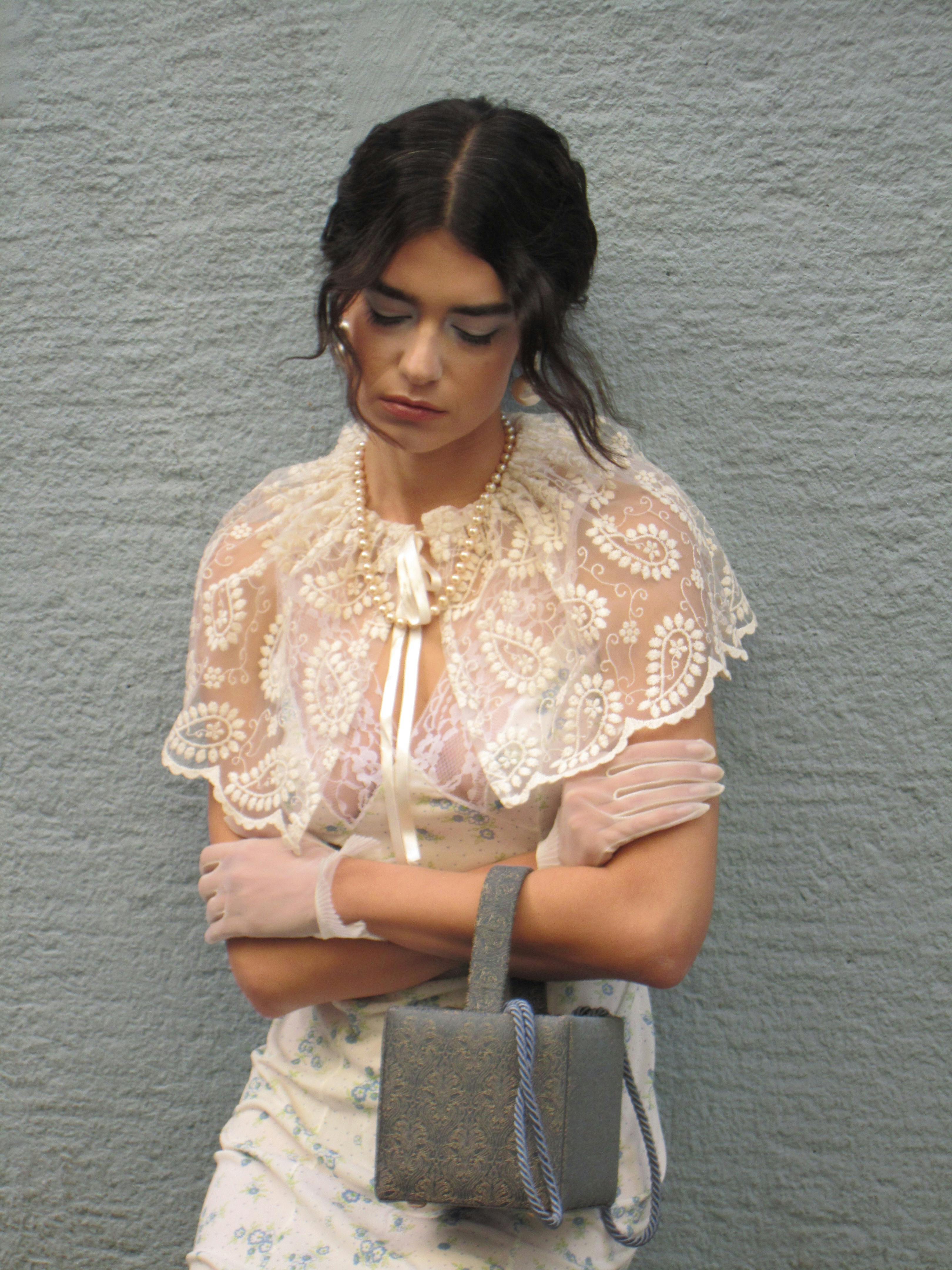 無料 屋外に立つ、手袋とハンドバッグを持ったヴィンテージのレースの衣装を着たスタイリッシュな女性。 写真素材