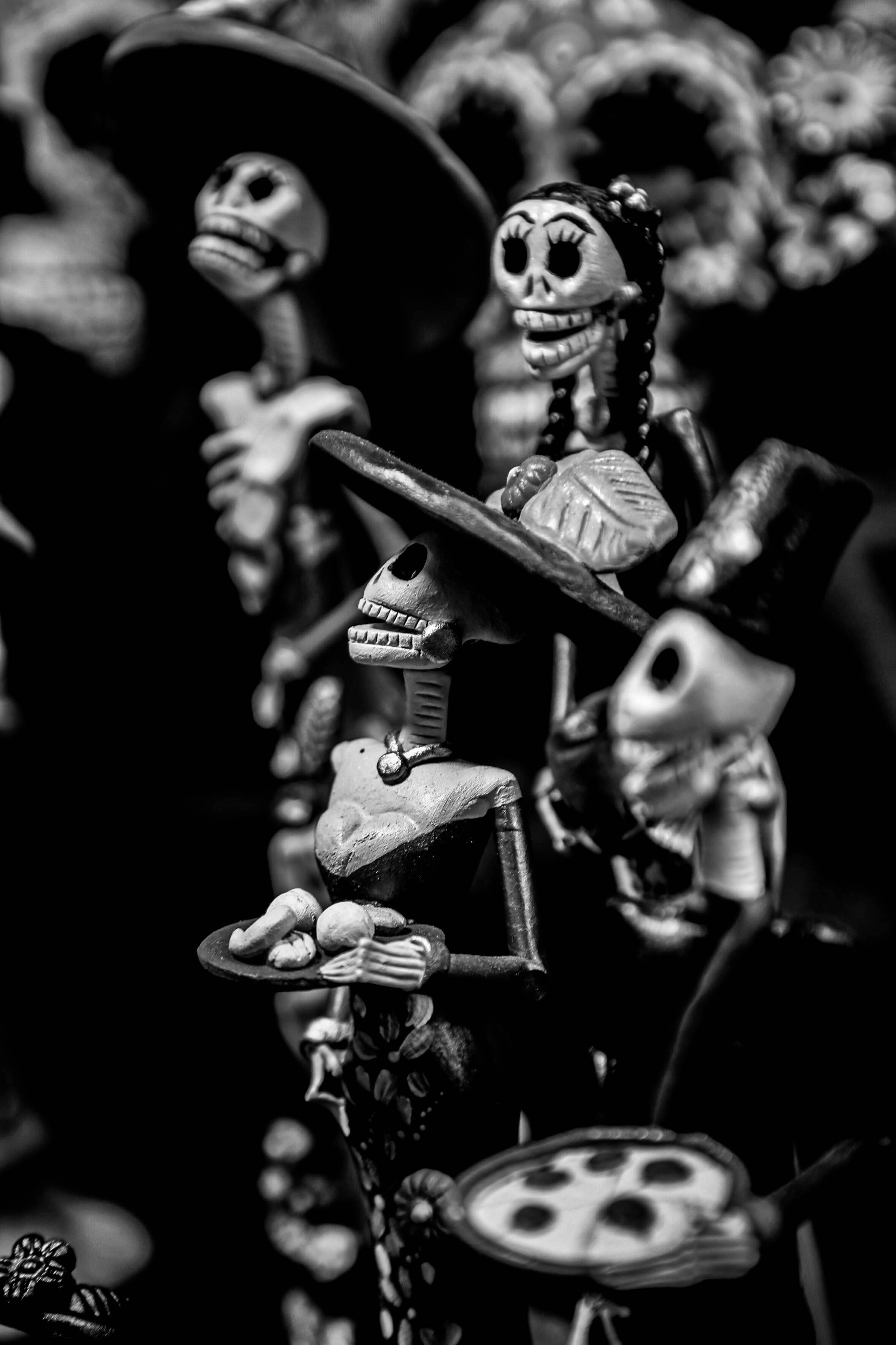 Artistic black and white photo of Day of the Dead skeleton figurines celebrating the festival.