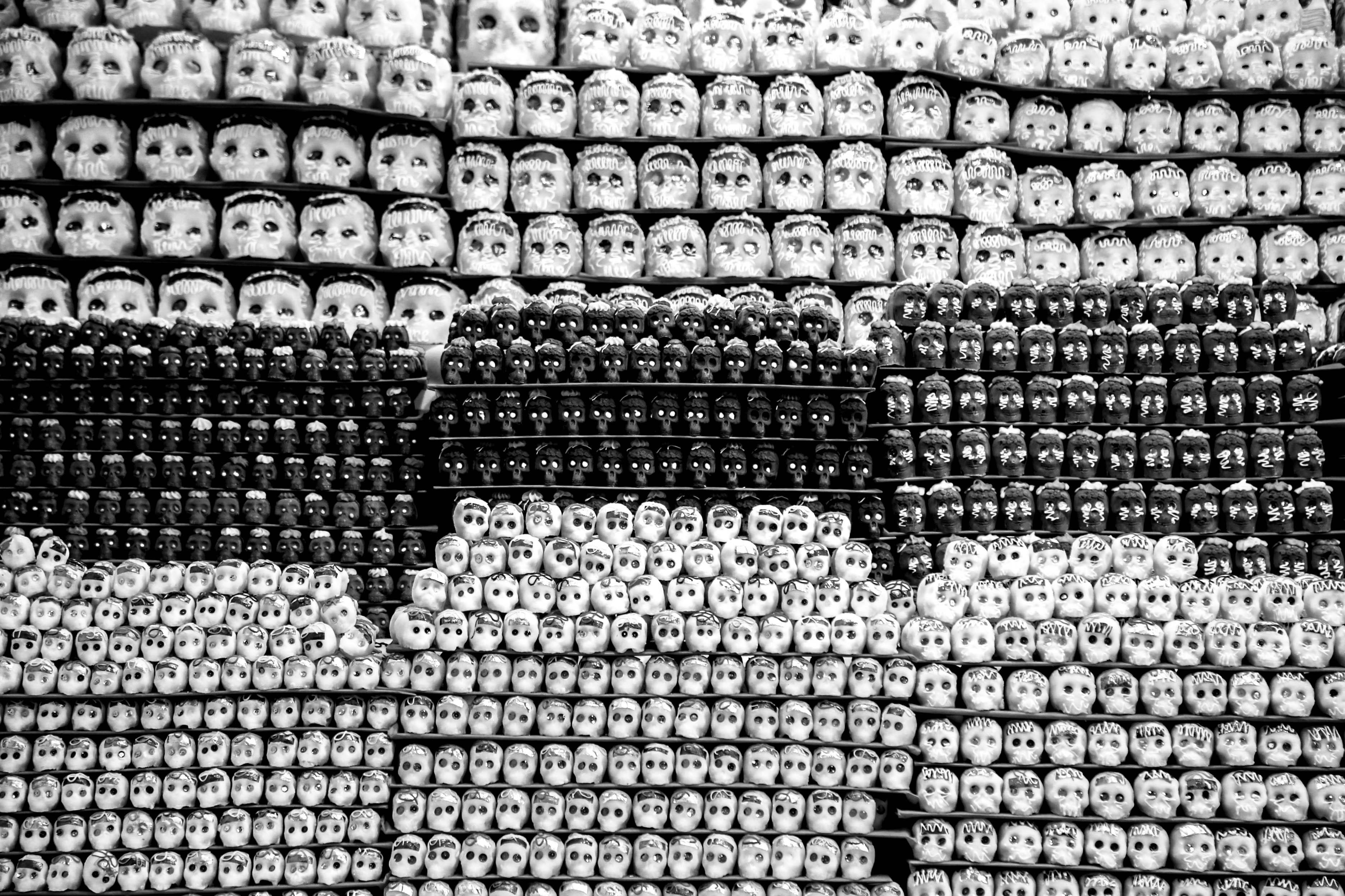 Black and white photo of stacked baby doll heads in rows, creating an abstract pattern.