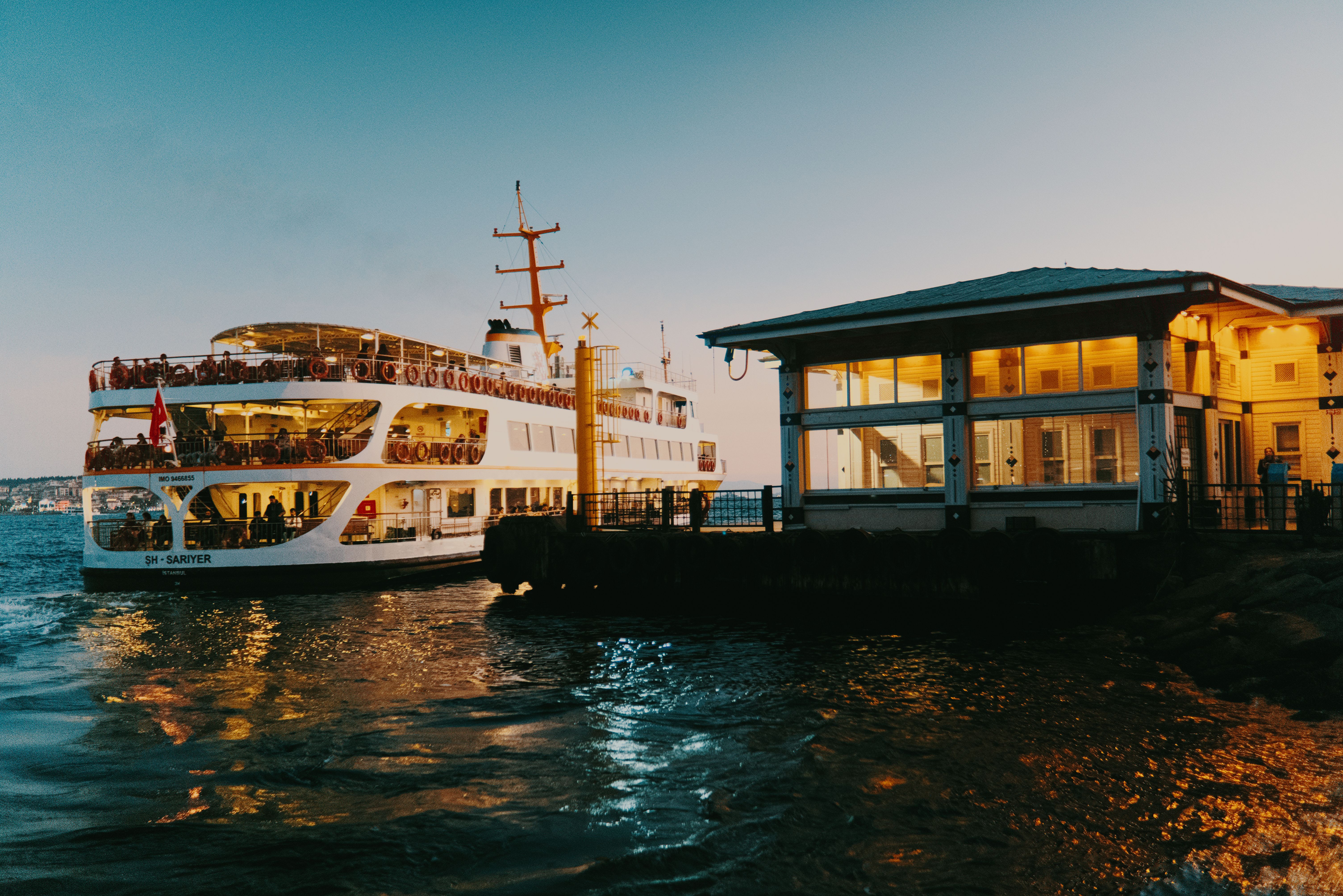 A wooden passenger ferry crossing the harbour towards Fort Kochi at dusk