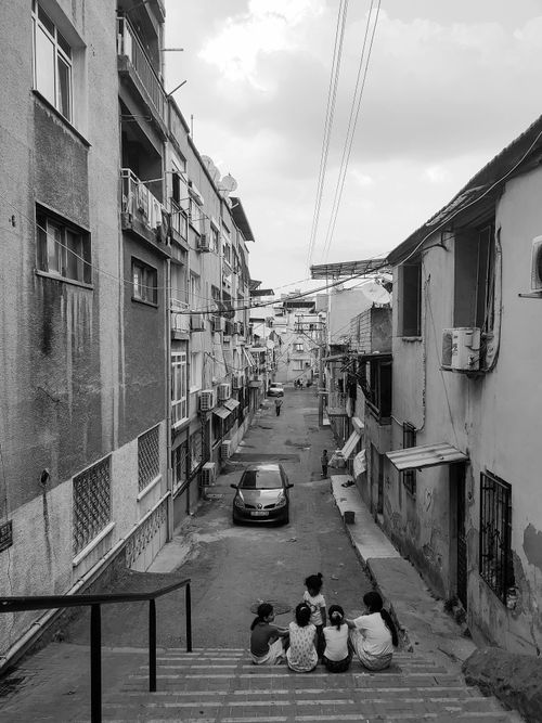 Free Monochrome image of children sitting on stairs in an urban street scene. Stock Photo