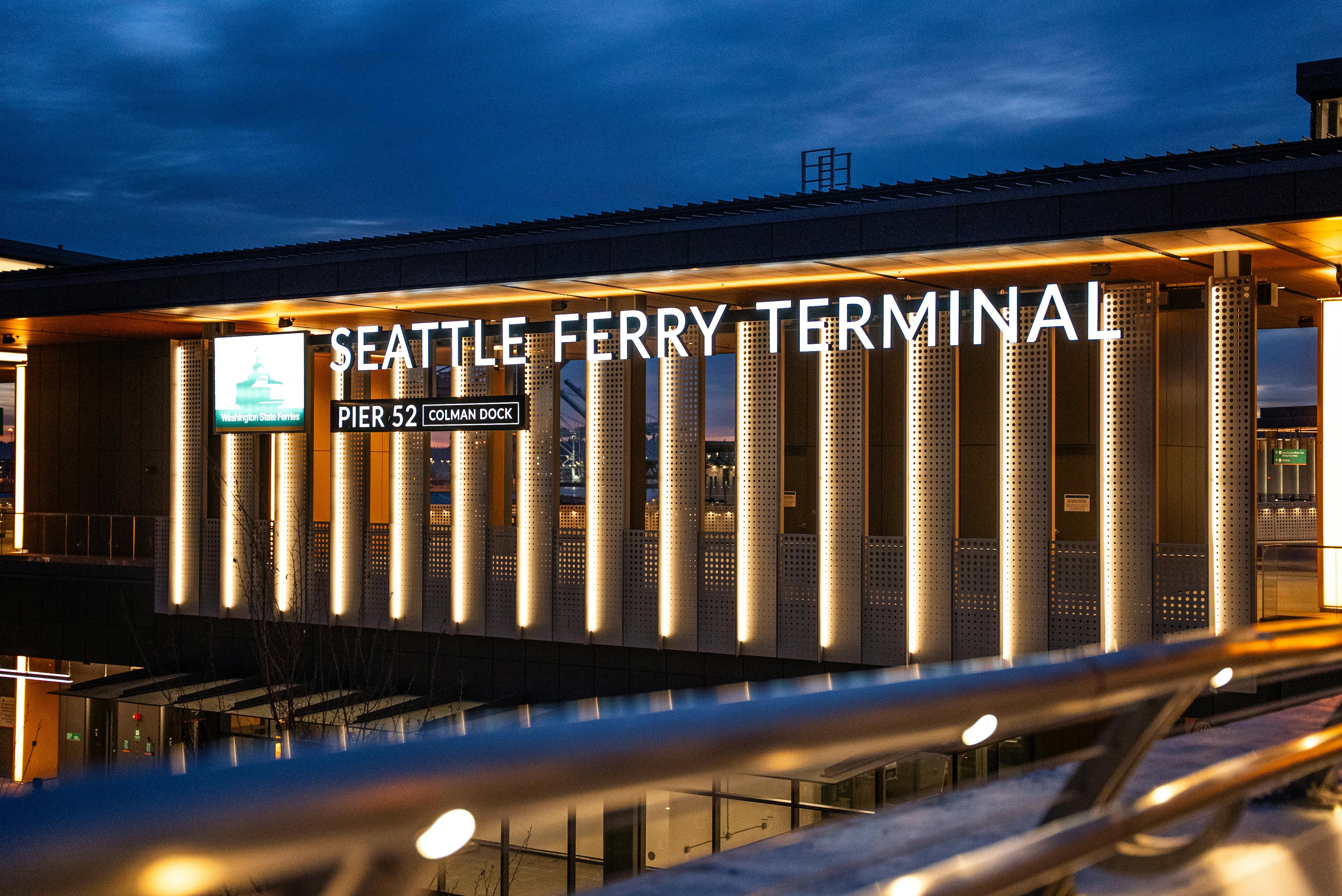 View of Seattle Ferry Terminal at night, showcasing illuminated signage and modern architecture.