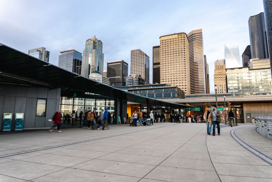 A bustling Seattle cityscape featuring modern skyscrapers and busy streets under a daytime sky.