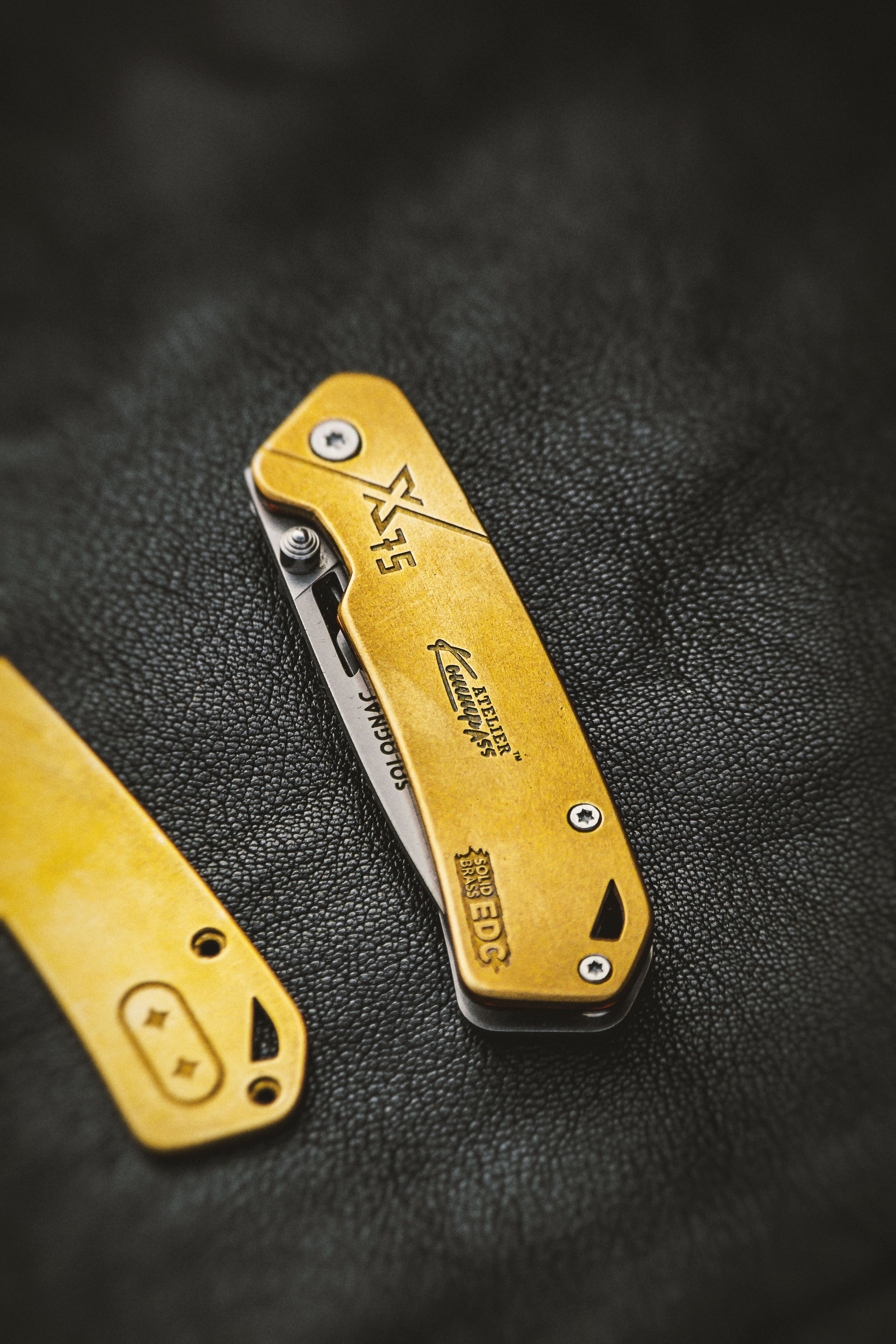 Elegant solid brass everyday carry (EDC) knife with custom design on black leather surface.