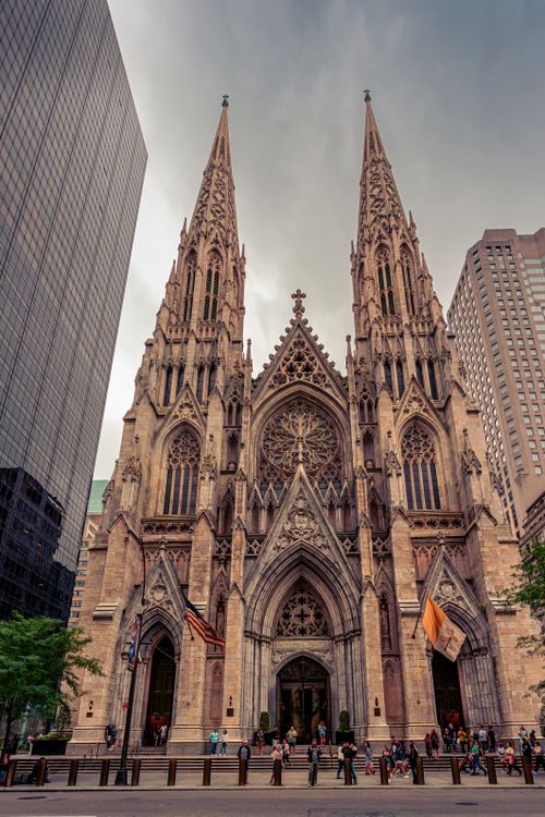 Free Gothic architecture of St. Patrick's Cathedral in NYC, with skyscrapers surrounding. Stock Photo