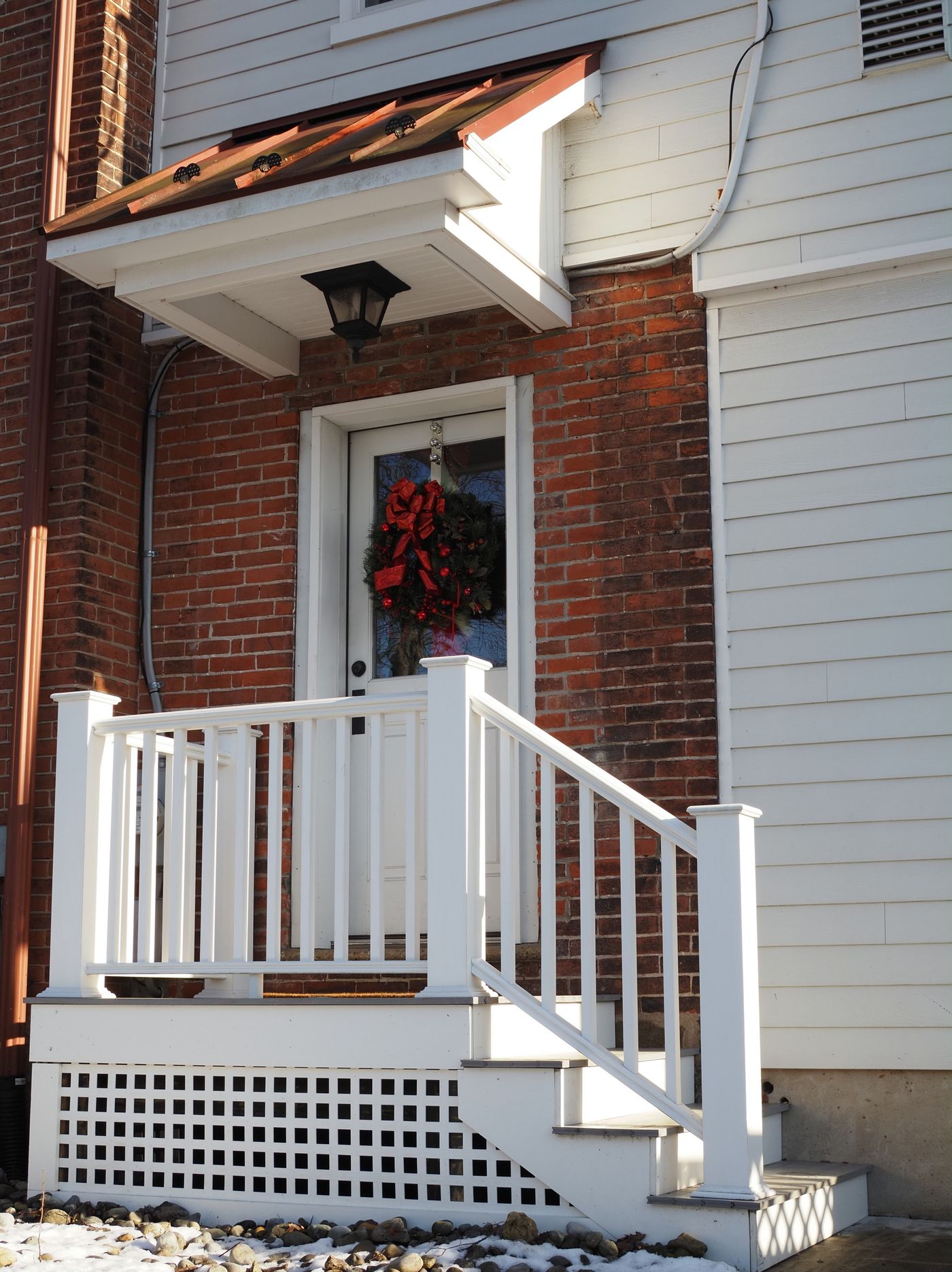 A charming front porch with a wreath, lit by bright winter sunlight