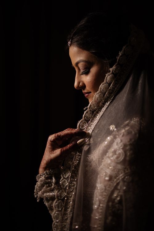 Free A bride in ornate traditional attire, captured in soft, dramatic lighting. Stock Photo