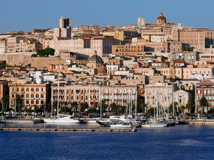 Discover Cagliari's vibrant waterfront, showcasing stunning architecture bathed in sunlight.