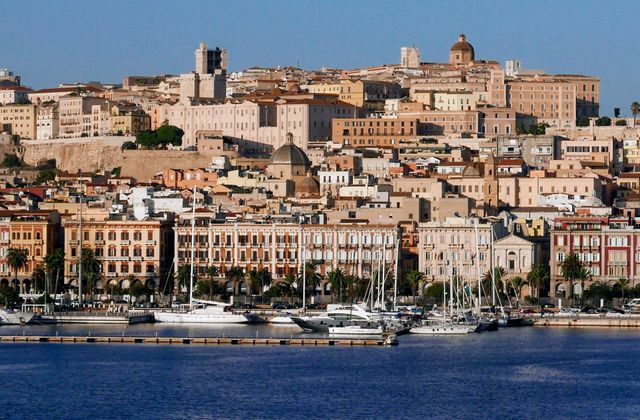 Discover Cagliari's vibrant waterfront, showcasing stunning architecture bathed in sunlight. — arriving in Cagliari