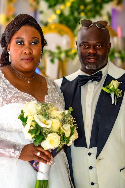 Free Beautifully captured wedding portrait of a smiling couple with floral bouquet. Stock Photo