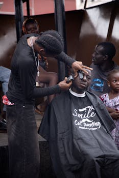 Outdoor barbershop with barber styling a man's hair while others wait.