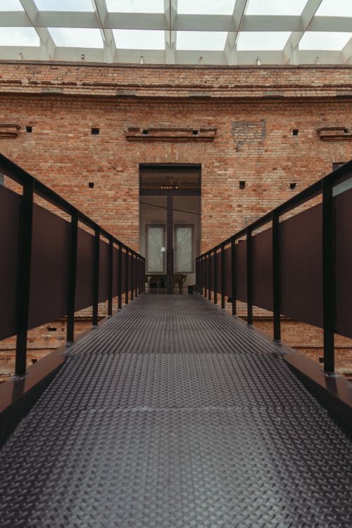 Free Architectural interior of a symmetrical footbridge with railings leading to a doorway in a brick art museum. Stock Photo