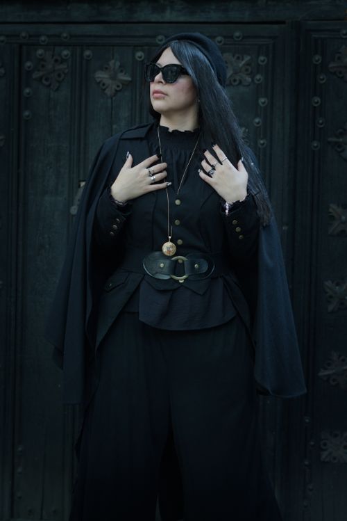 Free Stylish woman in Gothic fashion poses confidently near dark, ornate iron door. Stock Photo