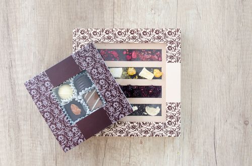 Free Delicious assortment of chocolates and sweets in beautifully designed boxes on a wooden tabletop. Stock Photo