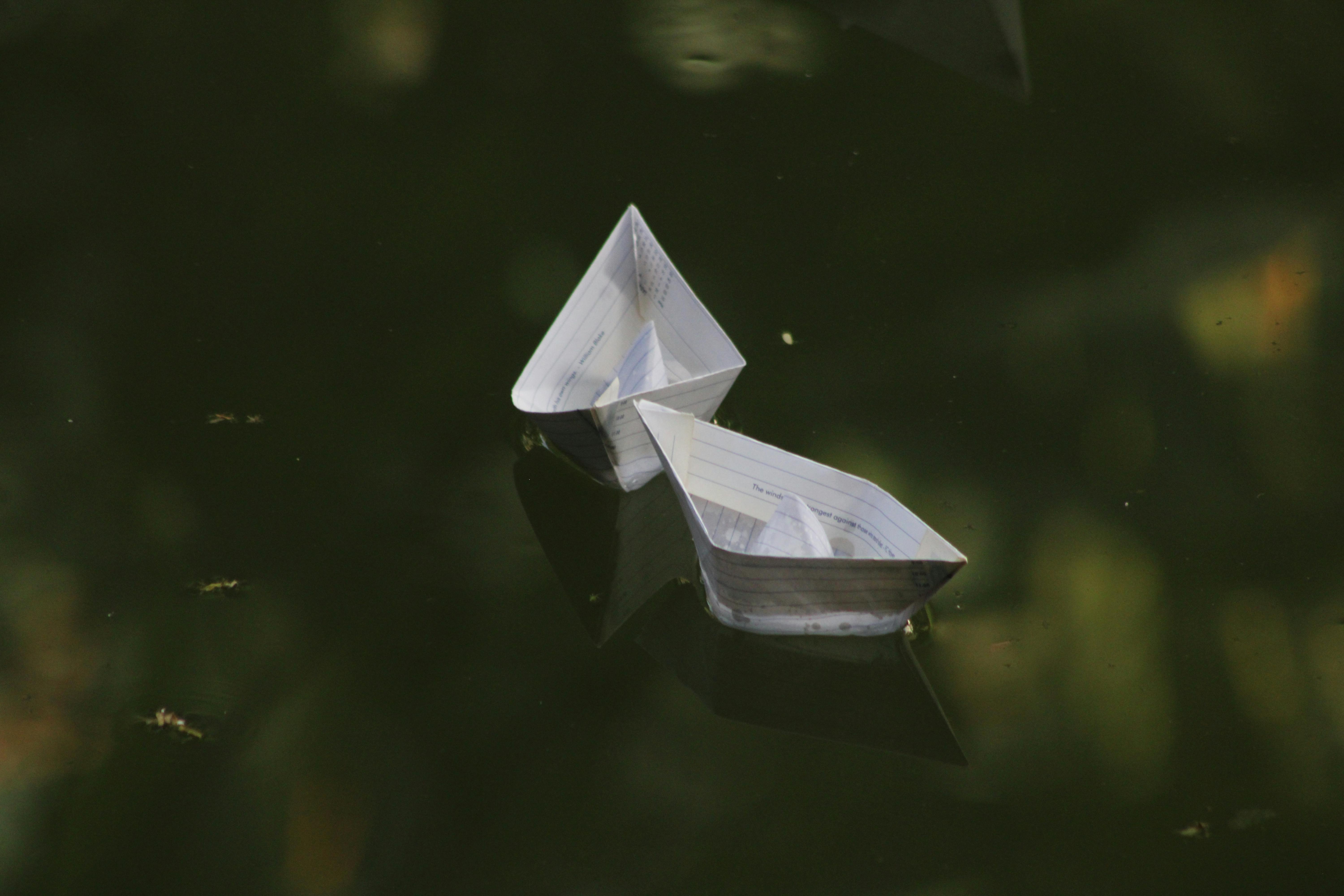 grátis Barquinhos de papel flutuando serenamente na superfície escura da água, refletindo tranquilidade e nostalgia da infância. Foto profissional