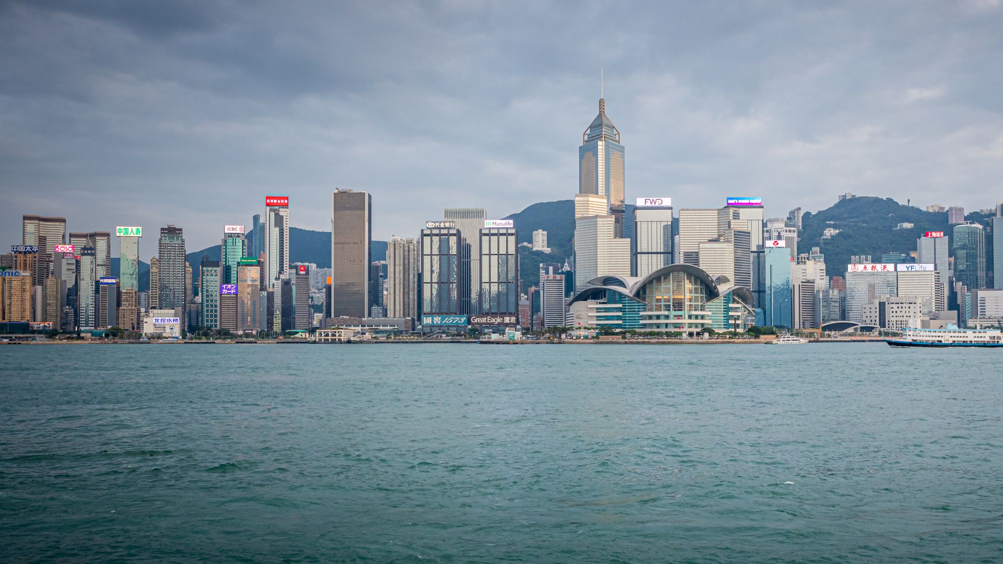 Spectacular daytime view of Hong Kong skyline with harbor in foreground.