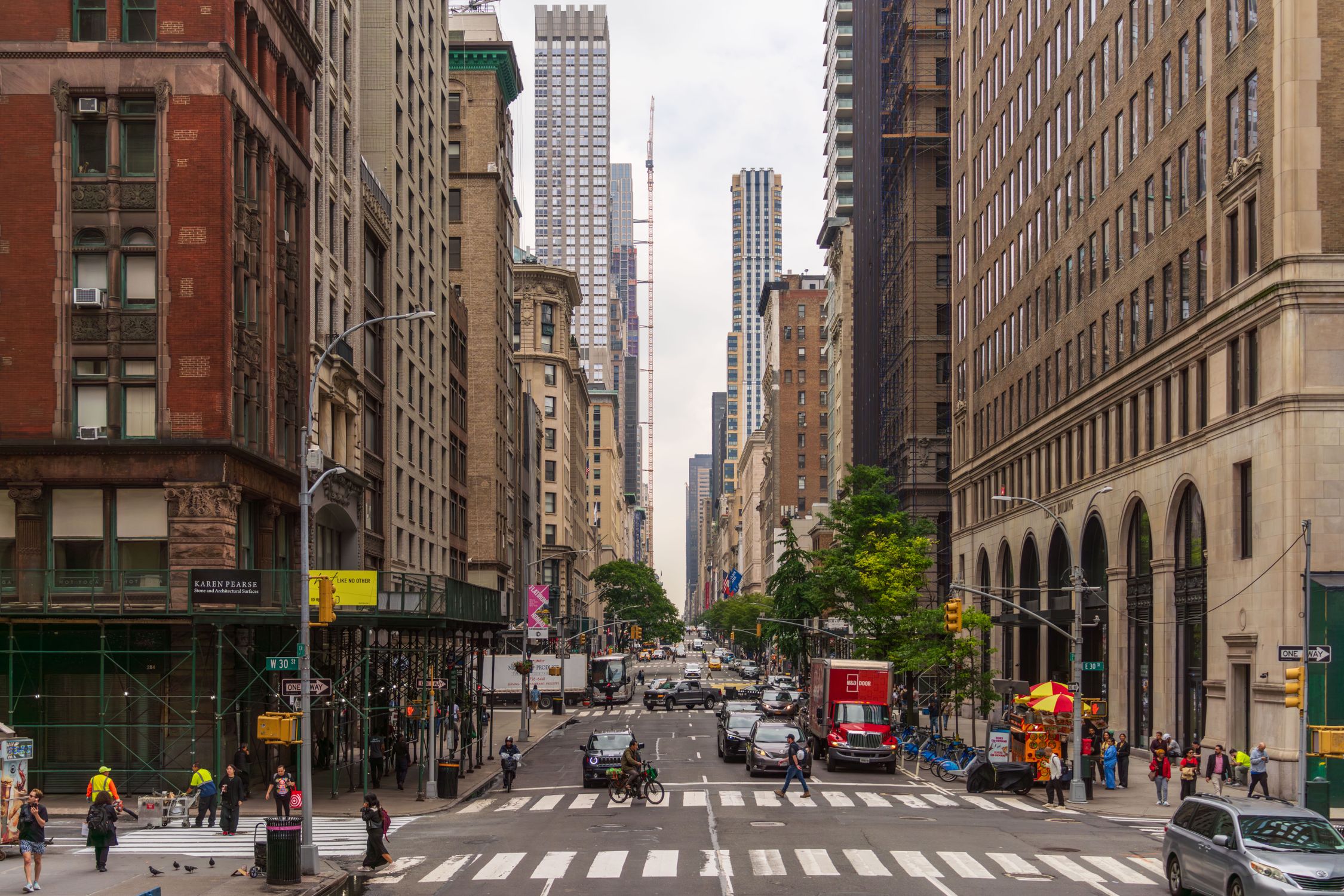 A busy street view of Midtown Manhattan with historic and modern buildings, pedestrians, and traffic