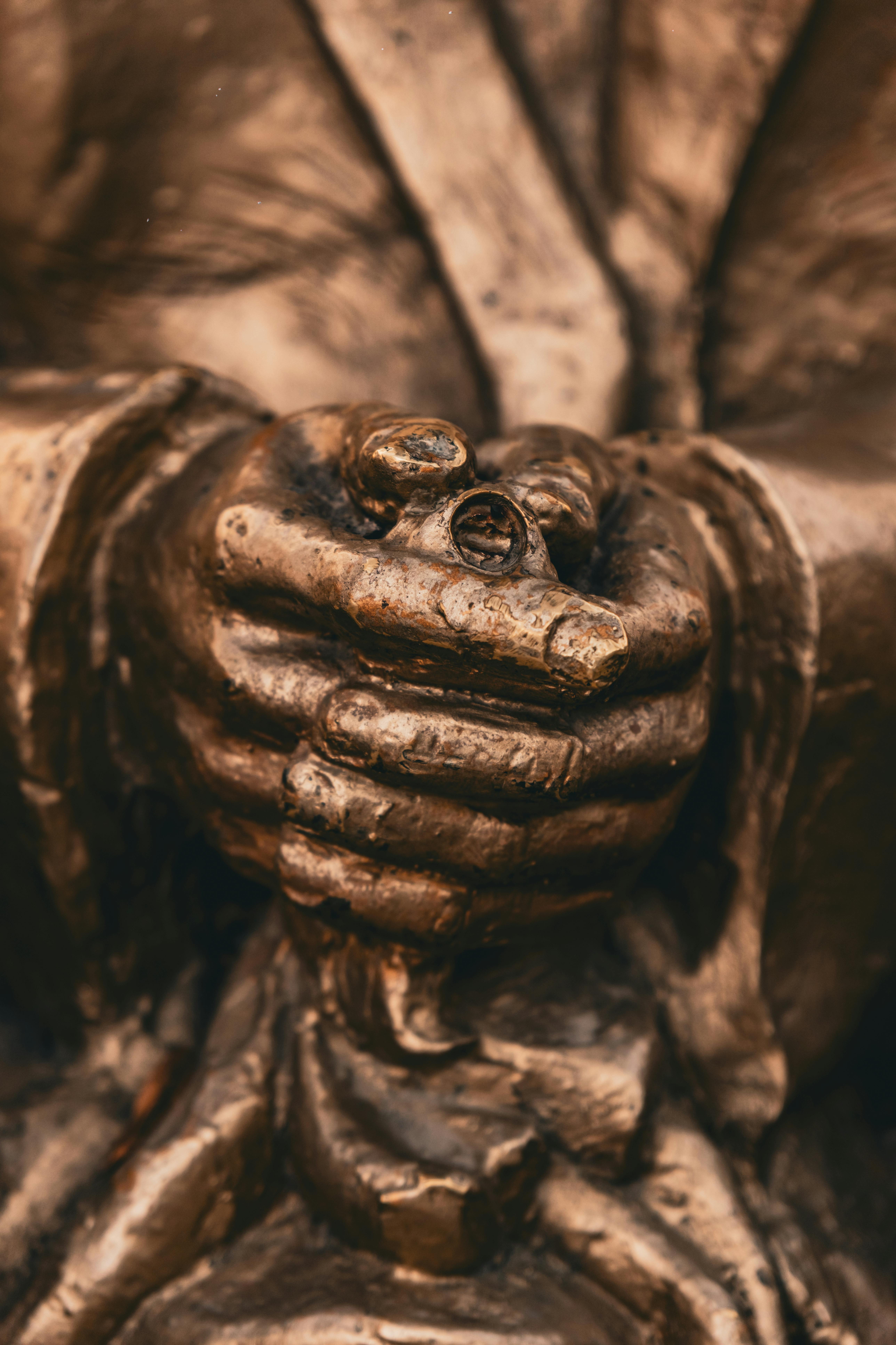 ingyenes Egy bronzszobor művészi közeli képe, amint finoman tartja a gyűrűt, kiemelve a textúrát és a patinát. Stockfotó