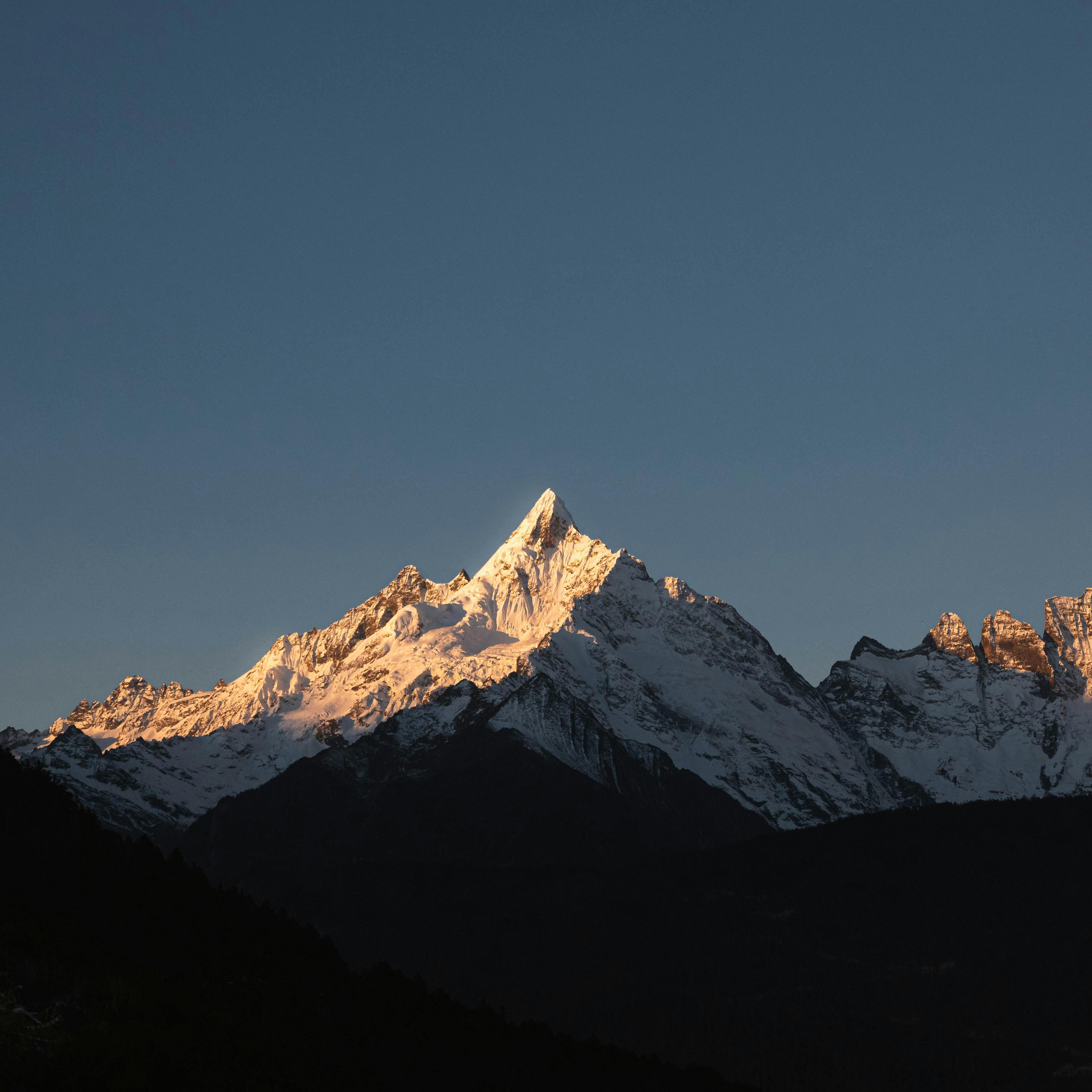 Stunning view of a snow-capped mountain peak illuminated by sunset light.