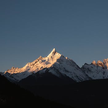 Stunning view of a snow-capped mountain peak illuminated by sunset light.