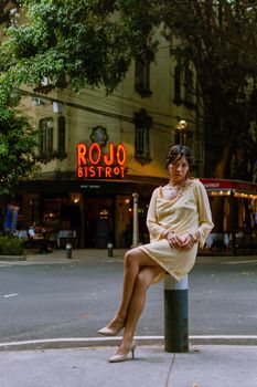 Stylish woman poses in a yellow dress in front of Rojo Bistrot, Ciudad de México, creating a chic urban vibe.