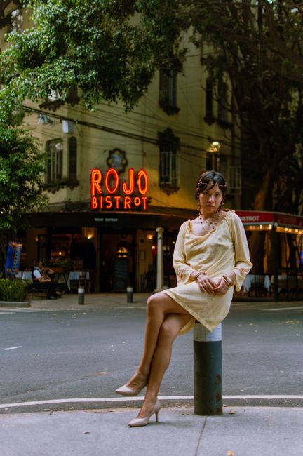 Stylish woman poses in a yellow dress in front of Rojo Bistrot, Ciudad de México, creating a chic urban vibe.