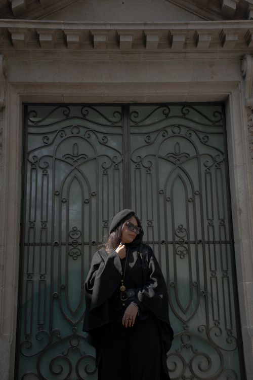 Free Woman in black outfit poses elegantly in front of a decorative metal door Stock Photo