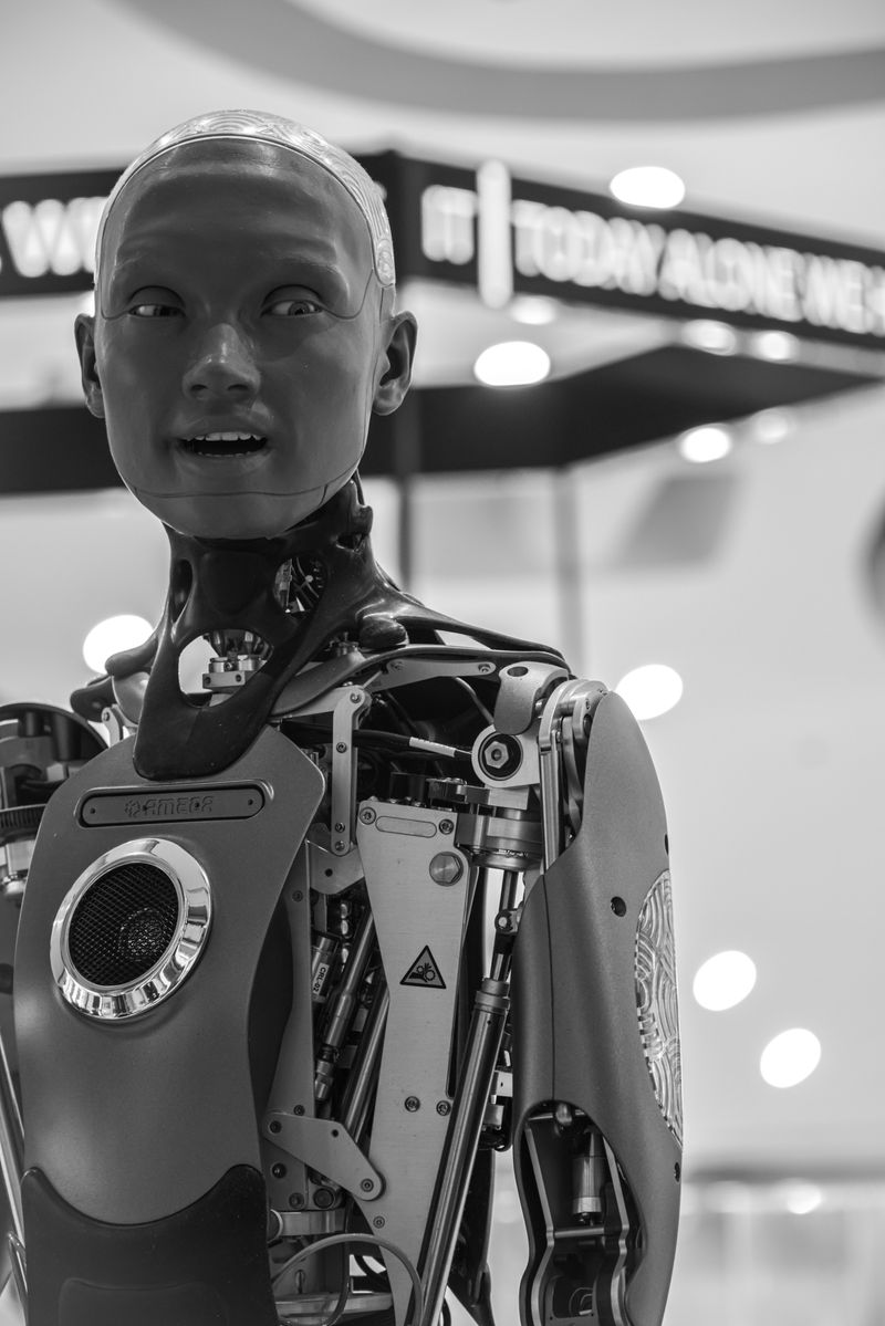 Ameca-style humanoid robot with exposed mechanics and realistic face at a tech exhibition