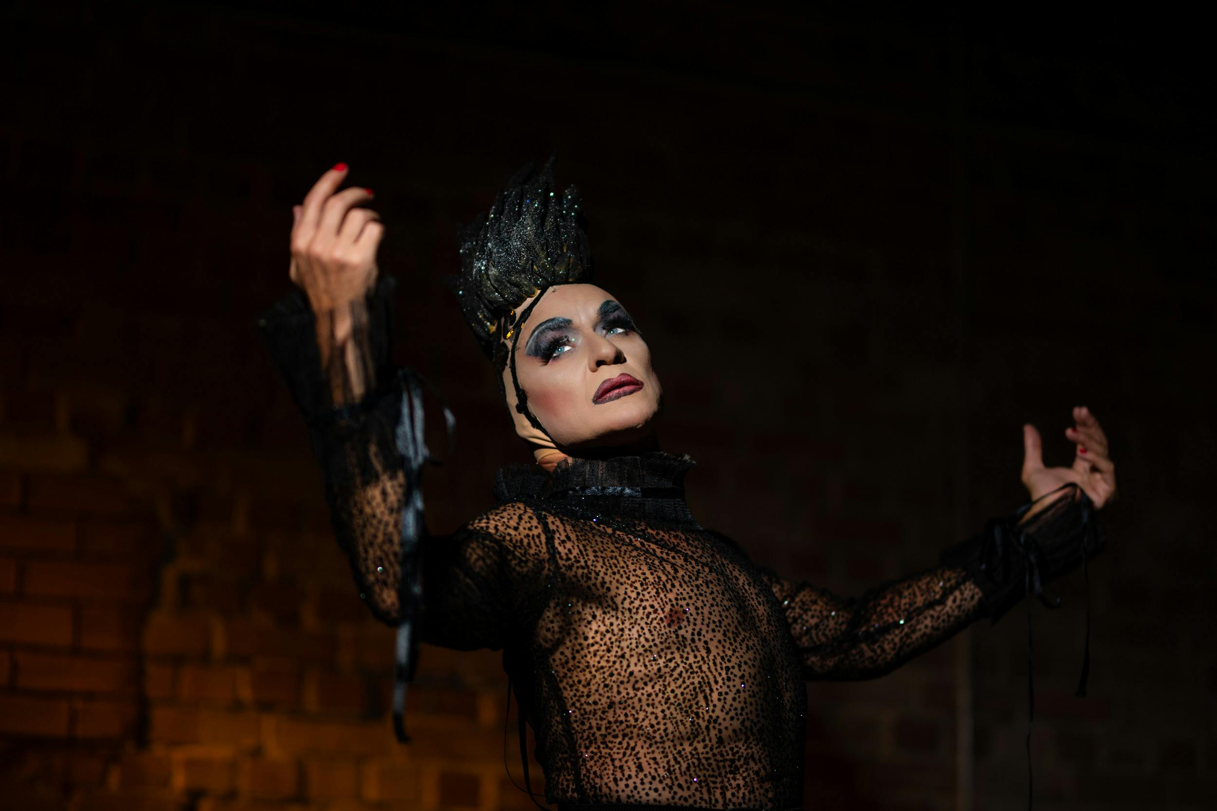 Ücretsiz Sahnede çarpıcı siyah bir kostüm giymiş, dikkat çekici bir performans sergileyen sanatçı. Stok Fotoğraflar