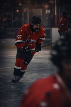 Hockey player in red jersey skating on ice rink during intense game moment.