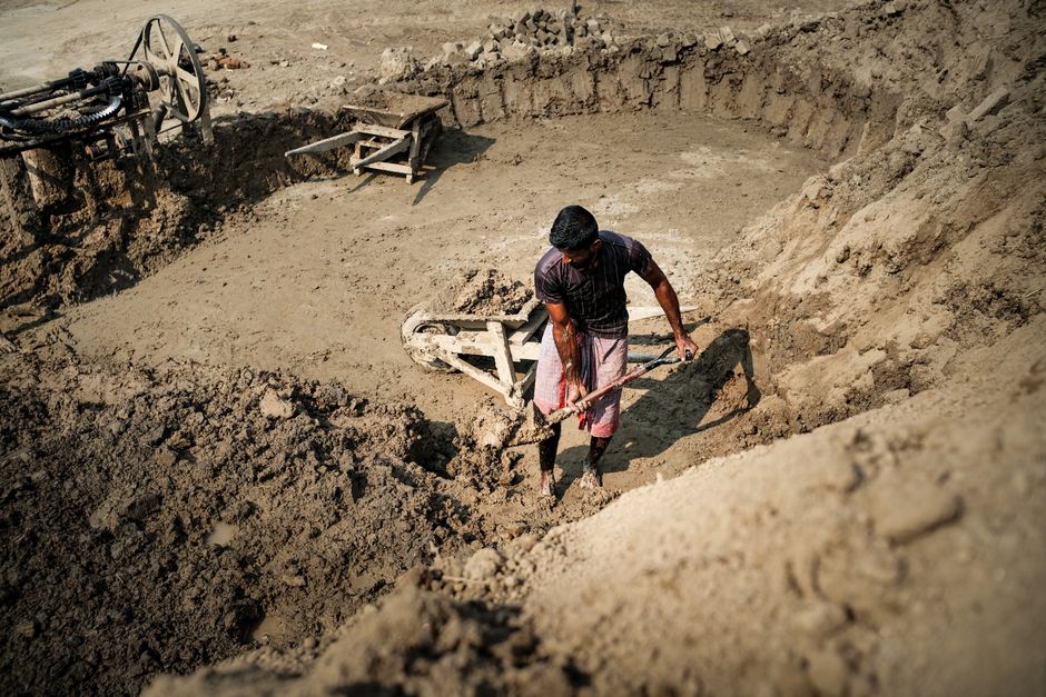 A worker digs in a construction site pit, showcasing manual labor and industry.