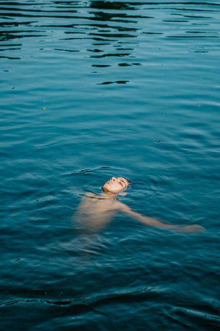 Serene image of a man floating on his back in calm blue water.