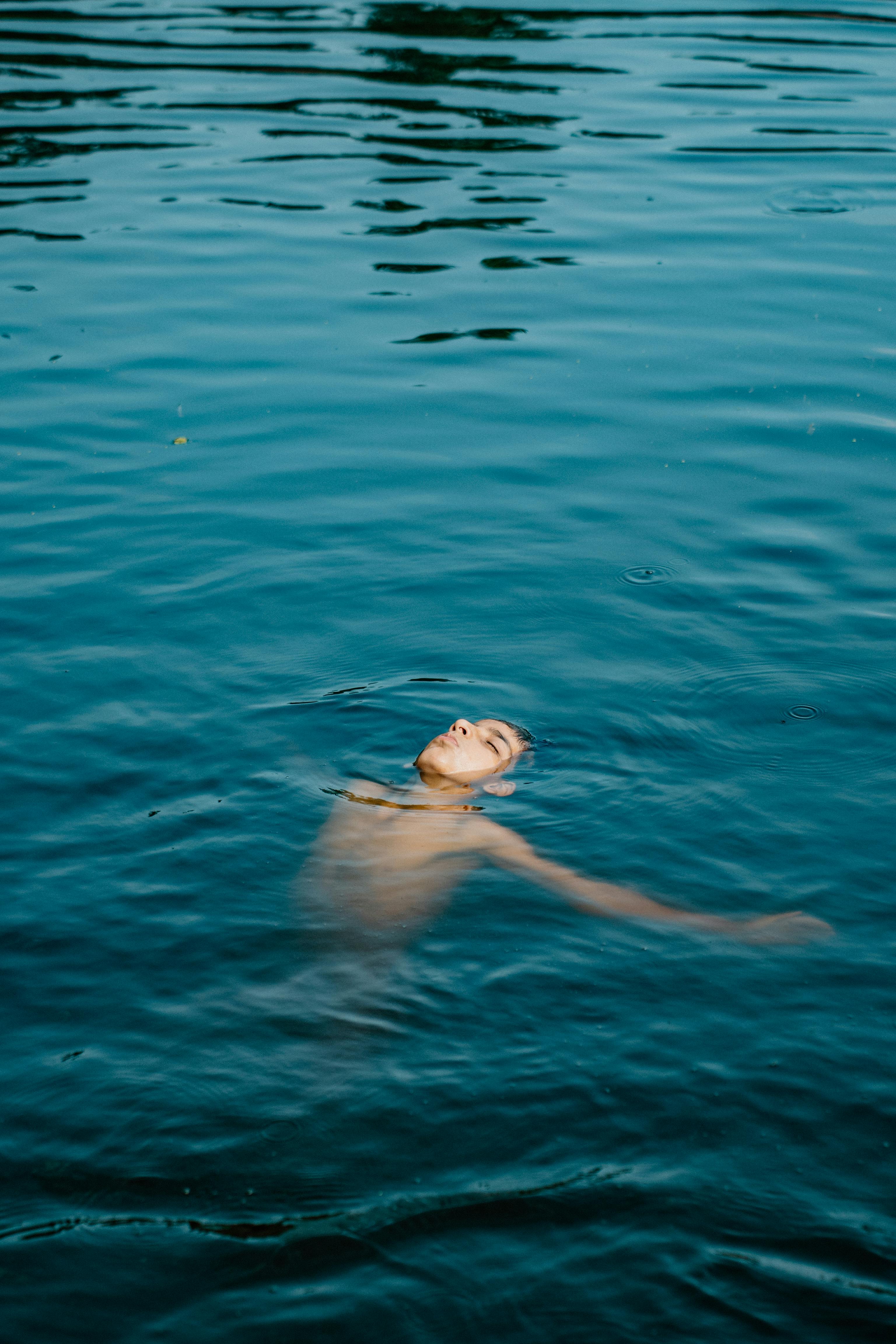 Gratuit Image sereine d'un homme flottant sur le dos dans une eau bleue calme. Photos