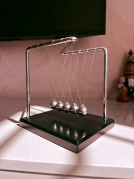 A sunlit Newton's Cradle on a shelf, showcasing physics in a modern setting.