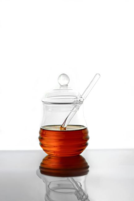 Elegant clear glass jar filled with honey, featuring a glass dipper, minimalist and sleek still life on a white background. - Factors to Consider When Selecting Honey