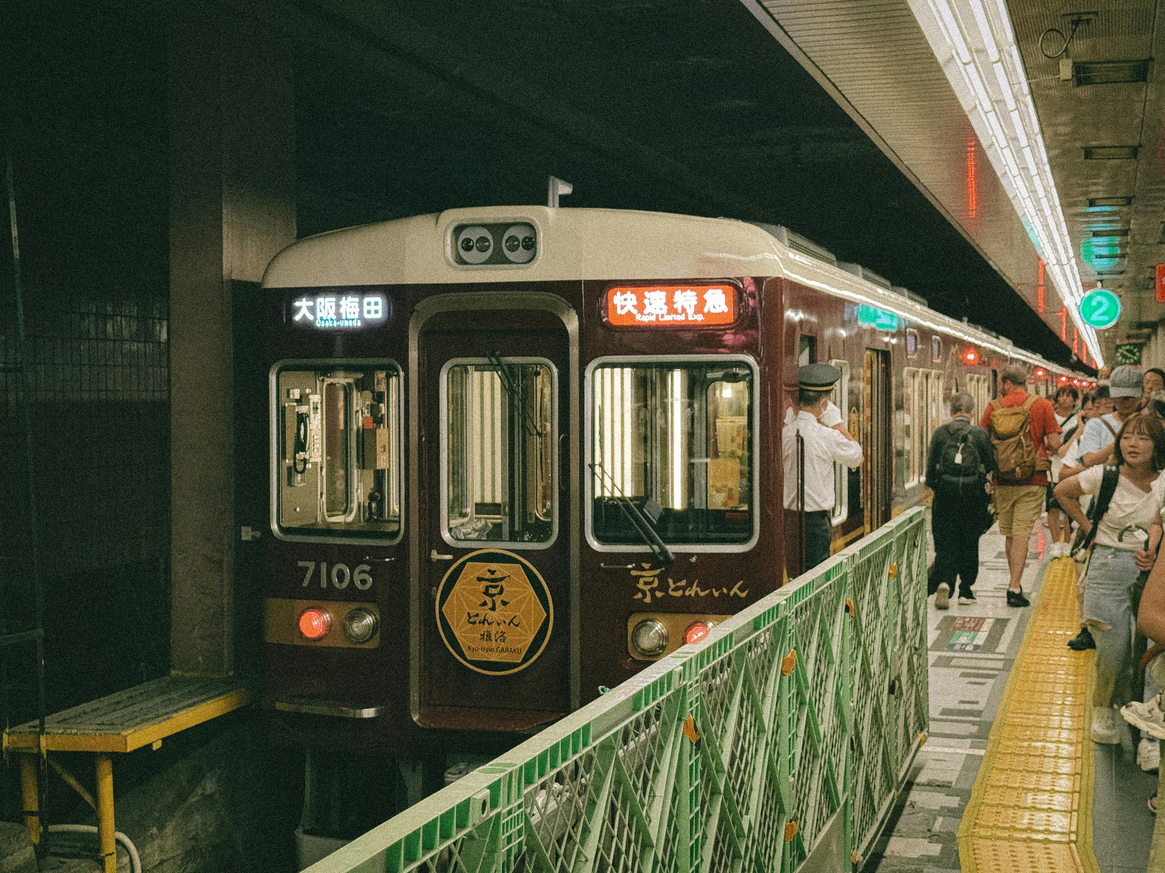 A bustling scene at Osaka Umeda Station with a vintage train and diverse commuters.