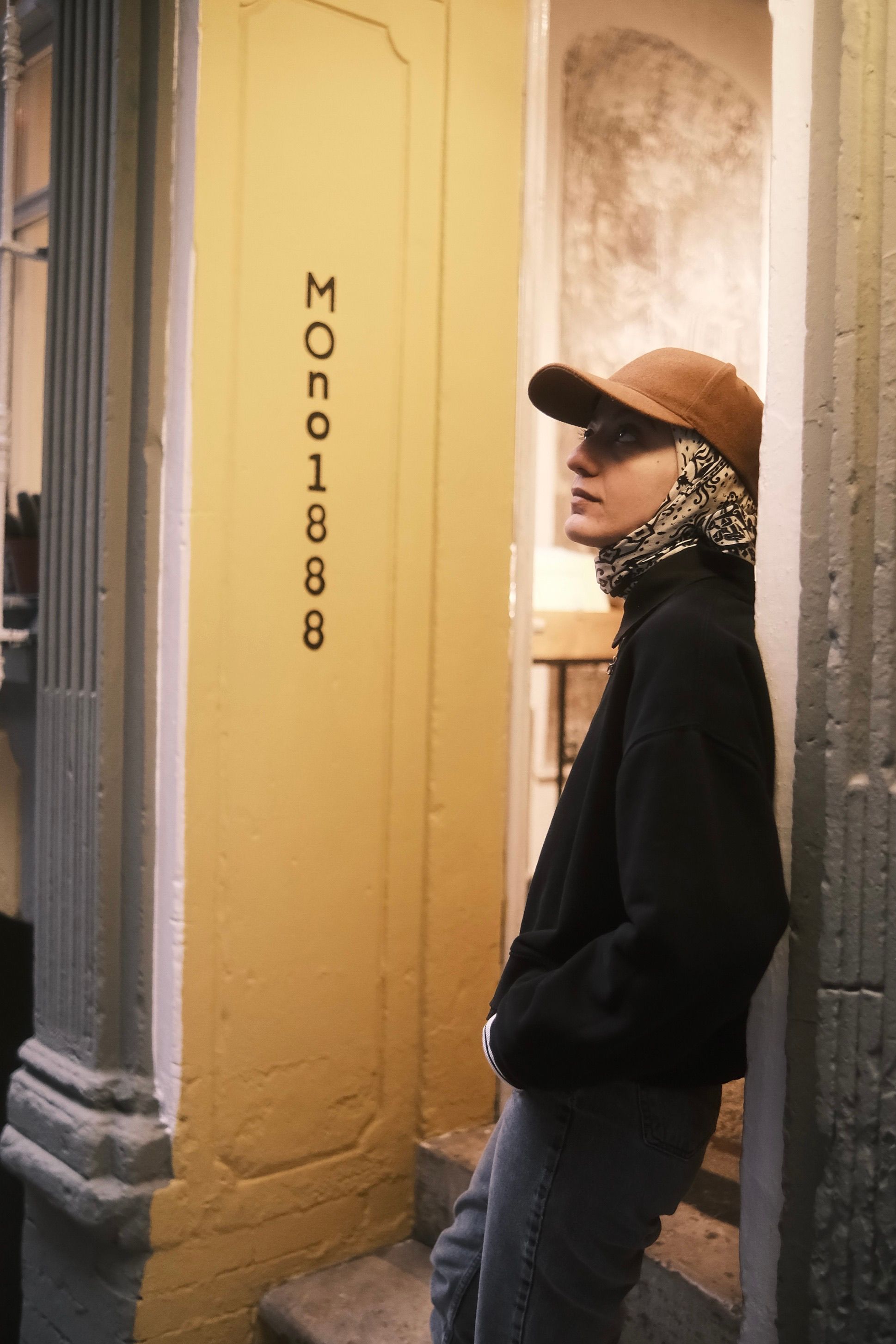 Profile portrait of a young adult leaning in a city alleyway, embodying urban style.