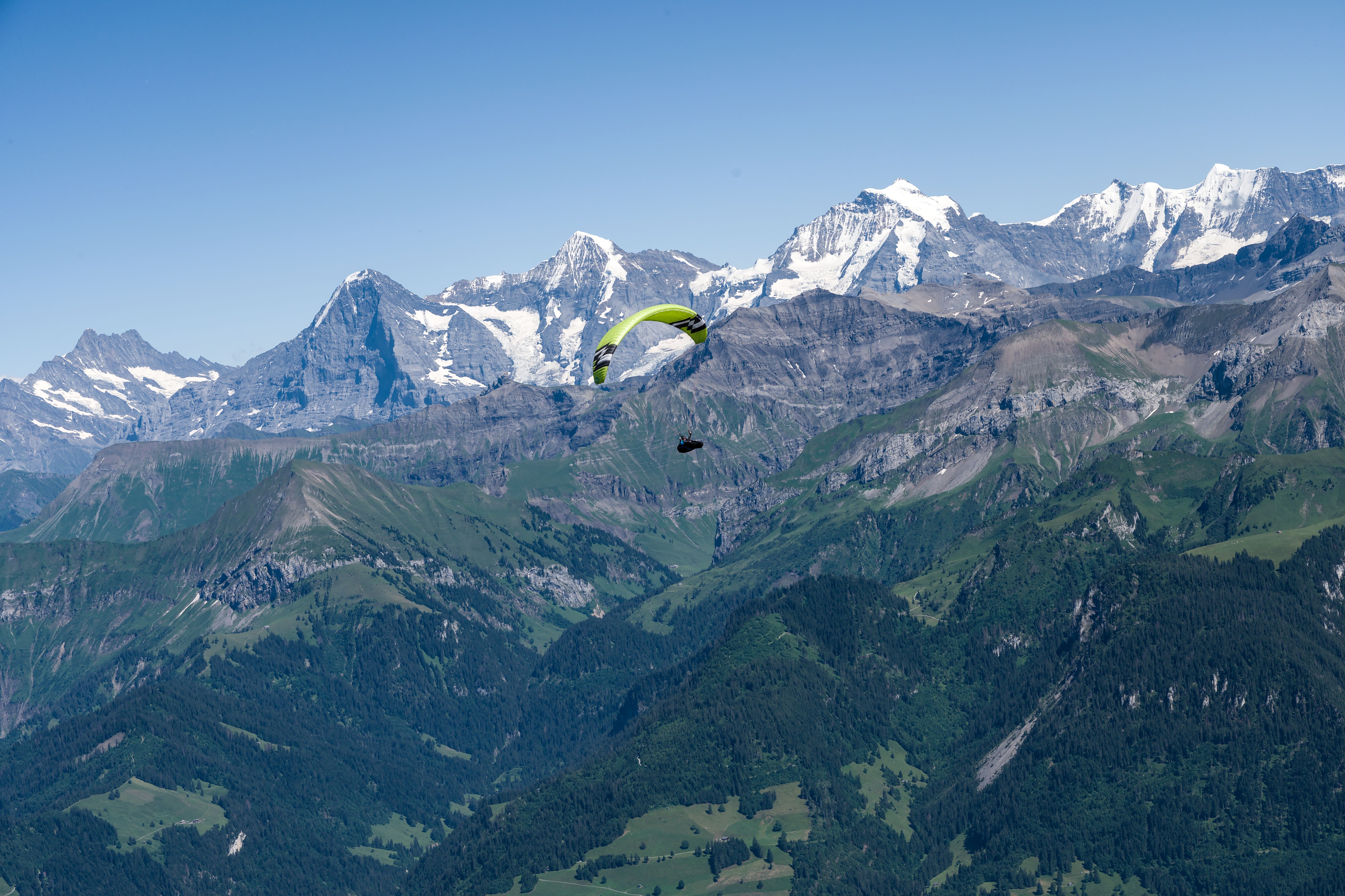Scenic view of a paraglider flying over the majestic Swiss Alps in summer.