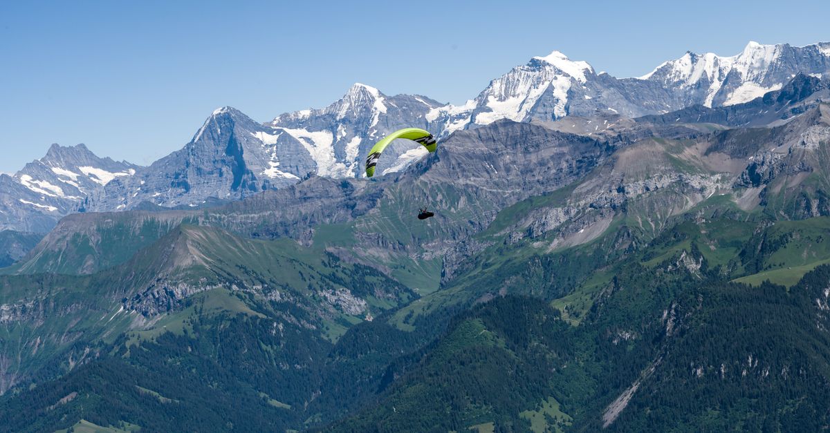 Scenic view of a paraglider flying over the majestic Swiss Alps in summer.