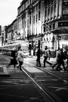 Black and white street scene in Dublin with tram and pedestrians crossing.