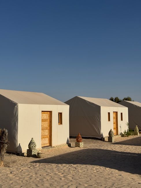 Luxury desert campsite with tents under a vibrant blue sky, perfect for unique travel experiences.