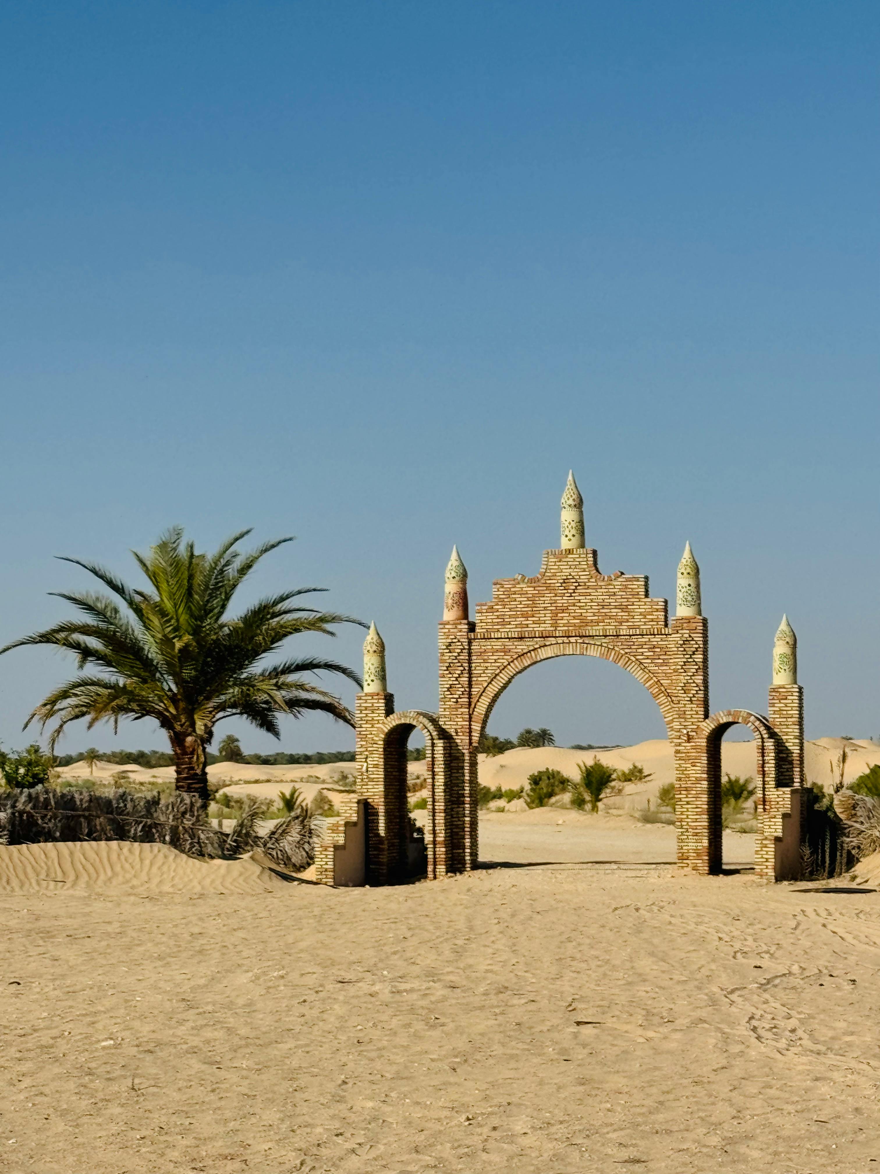 A solitary brick archway in a desert landscape with clear blue skies above.