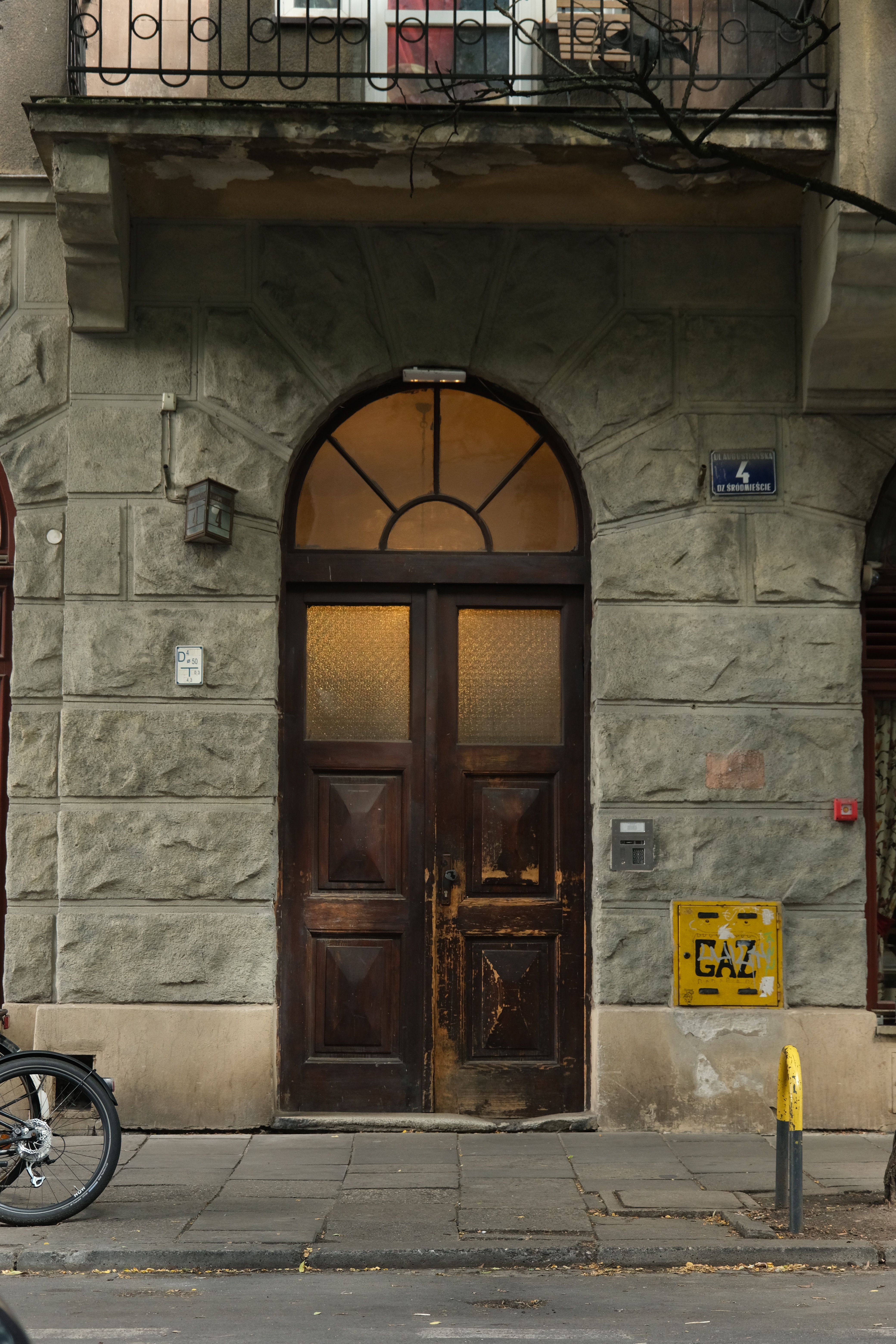A classic wooden door with arched windows set in a textured stone facade, offering a historic charm.